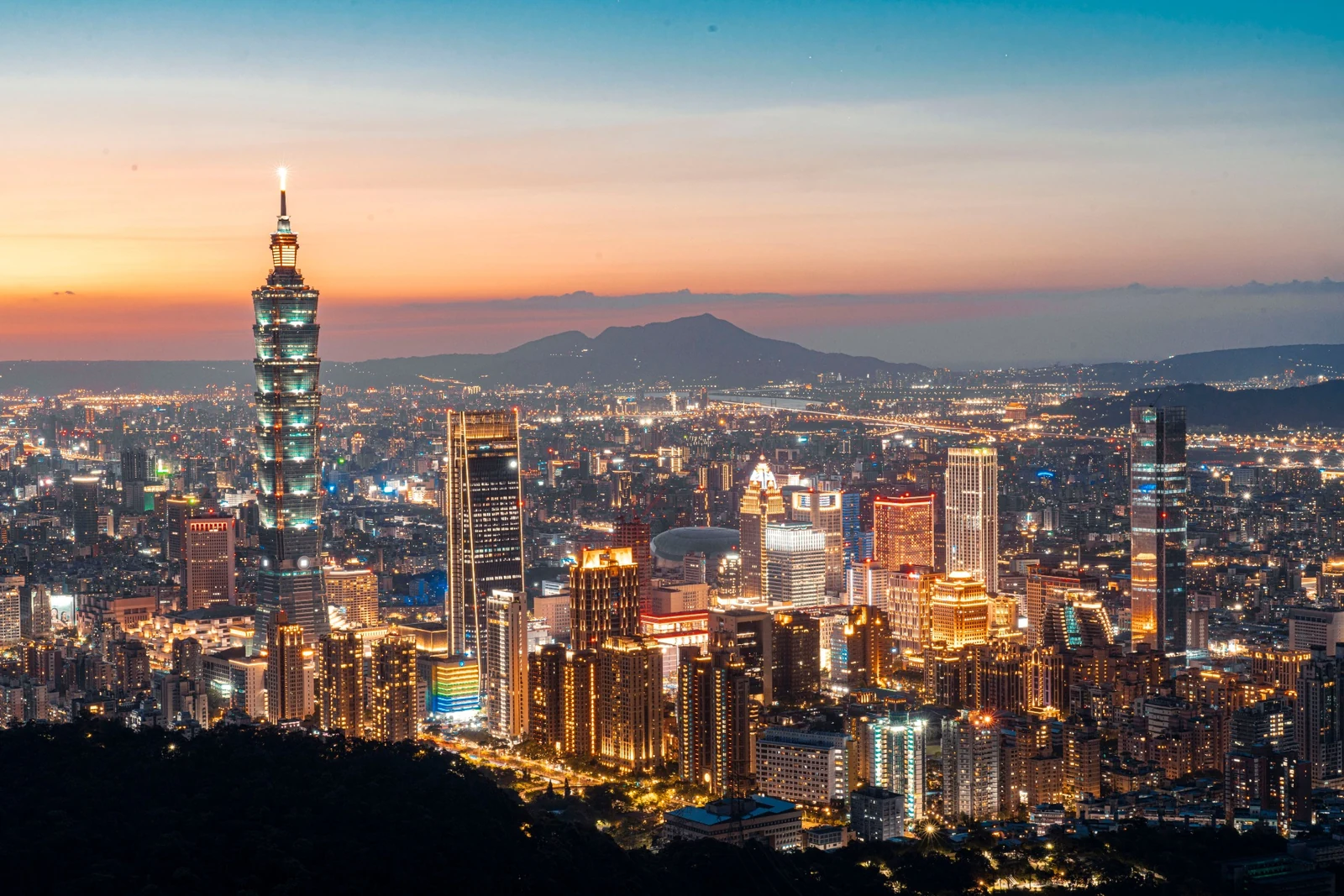Taipei 101 centered over the illuminated Taipei skyline at dusk